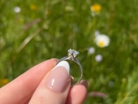 A beautiful continuum silver one and a half carat round brilliant moissanite ring, displaying the rainbow fire that is unique to this unique gemstone. This video has been shot in a field with wild flowers and you can hear the birds and wildlife in the back ground.