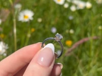 A beautiful white gold and one carat round brilliant moissanite ring, displaying the rainbow fire that is unique to this unique gemstone. This video has been shot in a field with wild flowers and you can hear the birds and wildlife in the back ground.