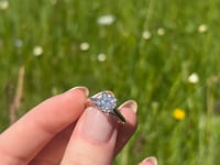 A beautiful white gold and one and a half carat cushion shape moissanite ring, displaying the rainbow fire that is unique to this unique gemstone. This video has been shot in a field with wild flowers and you can hear the birds and wildlife in the back ground.