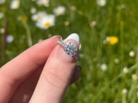 A beautiful white gold and one and a half carat round brilliant moissanite ring, displaying the rainbow fire that is unique to this unique gemstone. This video has been shot in a field with wild flowers and you can hear the birds and wildlife in the back ground.