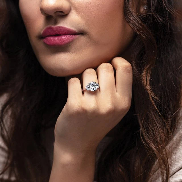 A lovely woman with pink lipstick is wearing a stunning yellow gold three stone engagement ring