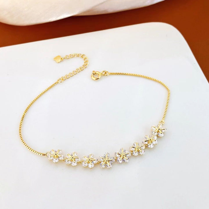 This charming sterling silver bracelet features delicate floral designs with sparkling cubic zirconia stones. The yellow gold plating adds a touch of elegance and helps prevent tarnishing, ensuring long-lasting beauty.