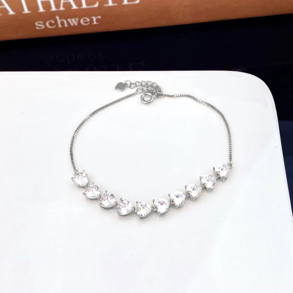 Elevate your style with this stunning sterling silver bracelet adorned with heart-shaped cubic zirconia stones. Each stone is meticulously set to create a captivating line of shimmering hearts that catch the light with every movement. The elegant design and sparkling accents make this piece a timeless addition to any jewellery collection.