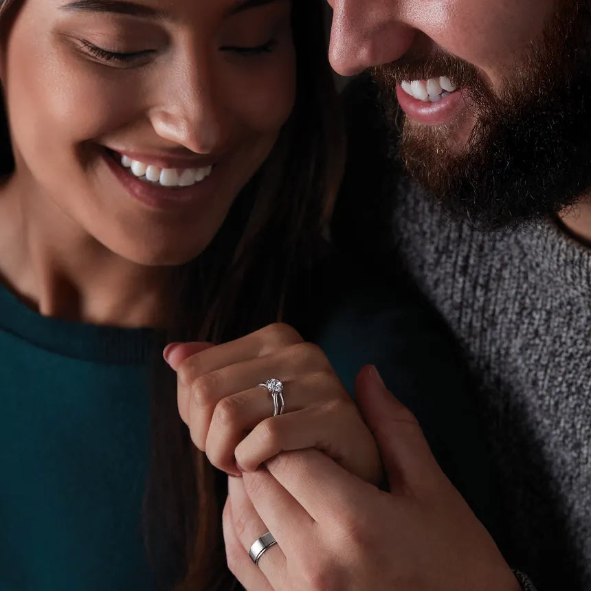 A woman wearing a ring standing next to a man